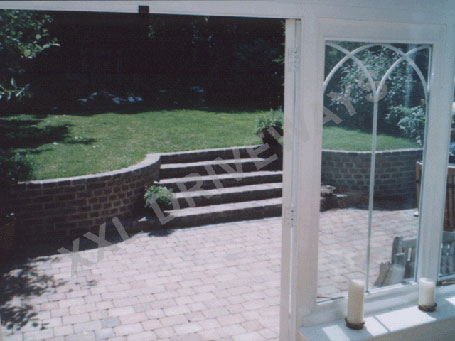 Block paved rear garden, brick wall including steps to new lawn.